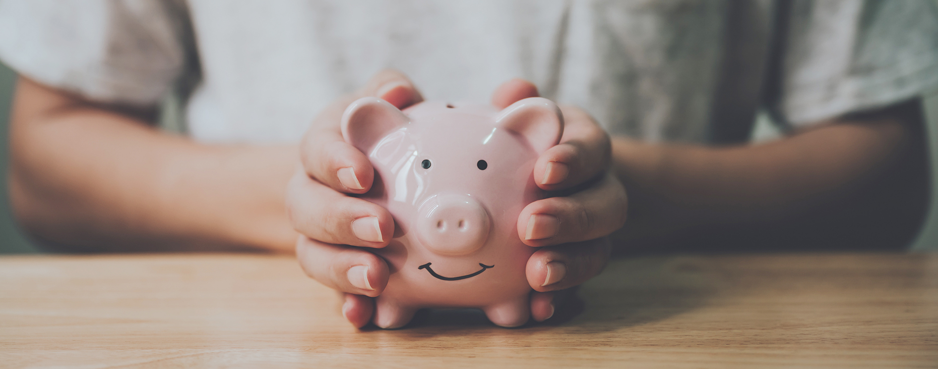 Panoramic,Image,,Man,Hand,Holding,Piggy,Bank,On,Wood,Table.